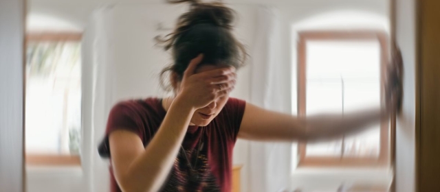 Woman bracing herself against doorframe, dizzy