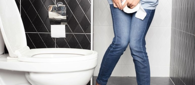 woman holding toilet paper over bladder next to toilet